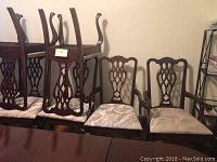 Eight chairs arranged against wall, two with arms and six without, some stacked upside down