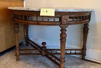 Full view of half-round hardwood console table showing cream marble top, carved legs, wooden stretchers, and minor damage on left leg.