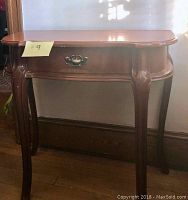Front view of the mahogany console table showing drawer with metal handle and curved legs.