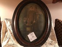 Vintage oval framed picture shown on a crochet fabric backdrop, displaying the woman portrait and frame condition with surface scratches.