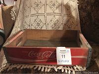 Front and inside view of the vintage Coca-Cola wooden box with red painted sides and metal corner supports, showing its worn condition.