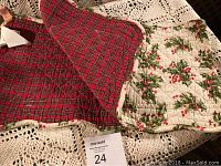 Quilted Christmas table runner with holly and berry pattern on one side and red plaid on reverse, folded showing both sides.