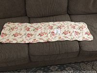 Photo of the floral cotton runner laid out on a brown couch.