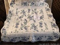 Photo of 22x22 inch floral patterned quilt laid out showing ruffled edges and quilting detail.