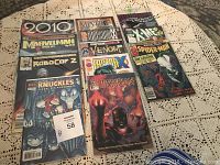 Photo showing all 12 comic books arranged on a table, each in individual protective plastic covers.