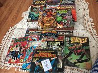 Various comic books laid out on fabric surface showing variety of titles and front covers.
