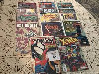 14 comic books arranged in two rows in plastic covers on a lace tablecloth, featuring various titles including Venom, Wolverine, X-Men, and Daredevil.