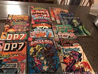 Overview of comic books laid out on a table, showcasing various titles including Omega Men, New Universe's D.P.7, Cyber Force, and Fantastic Four.