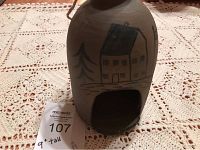 Front view of the 9 inch tall handmade clay bird house showing the painted house and tree design and square entrance.