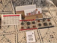 Photo showing the full set with original packaging, informational cards, and two plastic strips containing coins.
