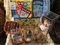 Four TY Beanie Babies animals in clear plastic display cases with attached heart-shaped tags, surrounded by three vintage children's game sets including Bingo and Kidz Cardz Go Fish.