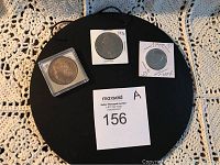Overview photo showing the three coins arranged on a black background with seller's MaxSold number card.