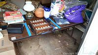 Full view of the folding table set up with assorted items on top, showing surface wear and the table's woodgrain Formica style top.