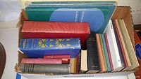 Box filled with antique and vintage books of various sizes and colors showing titles such as Egypt and other international-themed volumes.