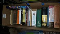 Wide overhead photo of box of classic books showing visible titles including Arabian Nights, Jane Austen, Shakespeare, and multiple other hardcover and paperback books.