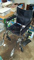 Black drive wheelchair with chrome frame and nylon seating, showing wear and tear.