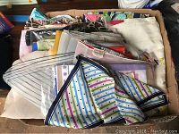 Photo showing a box filled with over 30 assorted women's scarves in various colors and patterns, including floral and striped designs.