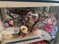 Various ribbons in multiple colors, textures, and sizes piled on shelving including loose pieces and spools.