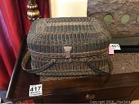 Front-side view of the rectangular woven basket with lid closed and visible metal latch, showing its condition and weave pattern.