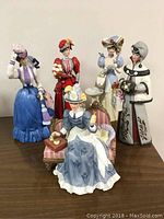 Front view of five detailed Mrs. Albee porcelain figurines in colorful period attire on display surface.