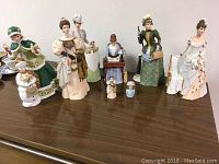 Set of all six Mrs. Albee figurines plus two mini figurines displayed on wooden surface, showing varied dresses and detailed painting.