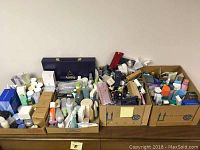 Four cardboard boxes filled with assorted Avon products including bottles, tubes, and boxed items