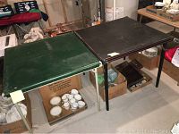 Photo showing two vintage card tables side by side in a basement setting. One has a green top with metal legs, the other a black top with wooden legs. Both measure 30 x 30 x 26 inches as per seller description.