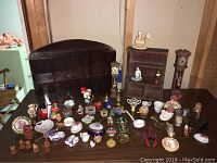 Wide overview of all items including two wooden whatnot shelves and an assortment of miniatures arranged on a table.