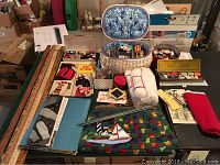 Photo showing entire sewing basket filled with sewing items including spools of thread, fabric, knitting needles, and various notions.