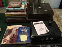 Overview of turntables, record albums stacked, and music books on table