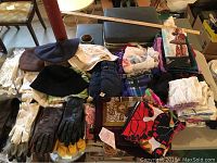 Wide view of hats, scarves, gloves and handkerchiefs spread out on table showing variety and condition