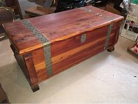 Front and side view of cedar blanket chest showing metal bands and lock with keyhole.