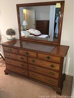 Front view of wooden dresser with large matching mirror behind.