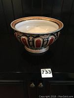 Full image of a heavy ceramic decorative bowl with red, blue, and gold pattern on pedestal base.