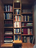 Full bookshelf with multiple shelves containing a variety of books including encyclopedias, fiction, and nonfiction titles.