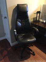 Front view of the black leather high back office chair with visible ergonomic contours and cushioned headrest.
