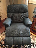Front view of the upholstered electric rocker recliner chair showing fabric pattern and padded armrests.