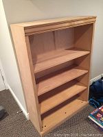 Full view of the solid wood bookshelf showing three adjustable shelves inside a rectangular frame.