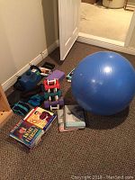 Overview photo showing blue yoga ball, dumbbells with rack, ankle weights, purple yoga block, multiple exercise books, and CableFlex personal gym unit.