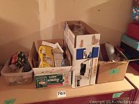 Multiple boxes and containers with various lightbulbs, including a clear glass globe bulb visible in one box, displayed on a table.