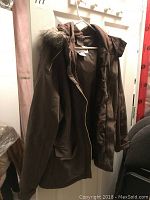 Dark titanium-colored Columbia women's coat size XL hanging on a door, showing fur-trimmed hood and front pockets.