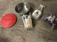 Photo showing a red KONG frisbee, stainless steel dish, dog deodorizer spray, container with dog message cards, and a resealable bag with some items.
