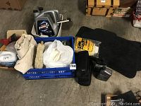 Overview photo showing the collection of motor oil, floor mats, antifreeze, sponges, carrying case, and crate with cloths/cleaning items arranged on concrete floor.