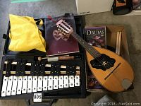 Overview showing mandolin, xylophone case, drum pad components, DVD and book