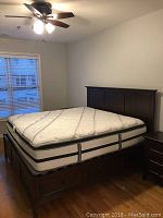 Side view of white and gray Beautyrest mattress on dark brown wood platform bedframe with storage drawers