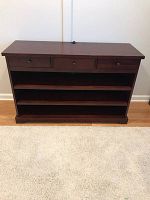Front view of console table showing three drawers, two shelves, mahogany finish