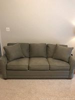 Front view of the olive microfiber queen sleeper sofa showing cushions and pillows