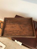 Top-down view of the wooden tray showing the rectangular surface with wood grain and two metal handles on short sides.
