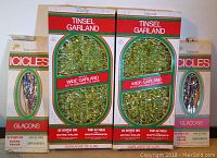 Photo showing two unopened packages of Victoria brand wide tinsel garland and two packages of silver icicles.