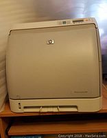 Front view of HP LaserJet 1600 color printer showing control panel, HP logo, and paper output tray.